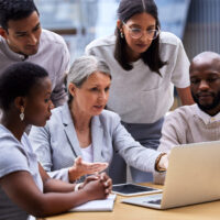 Shot of a group of professional coworkers using a laptop together at work.